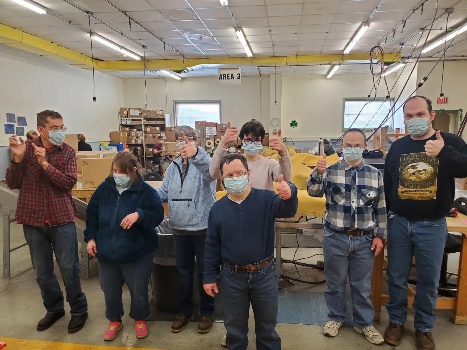 Creekside Industries team members giving a thumbs-up on the production floor